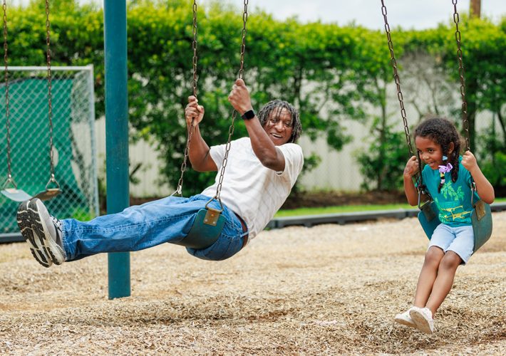 Father and daughter playing on the swing